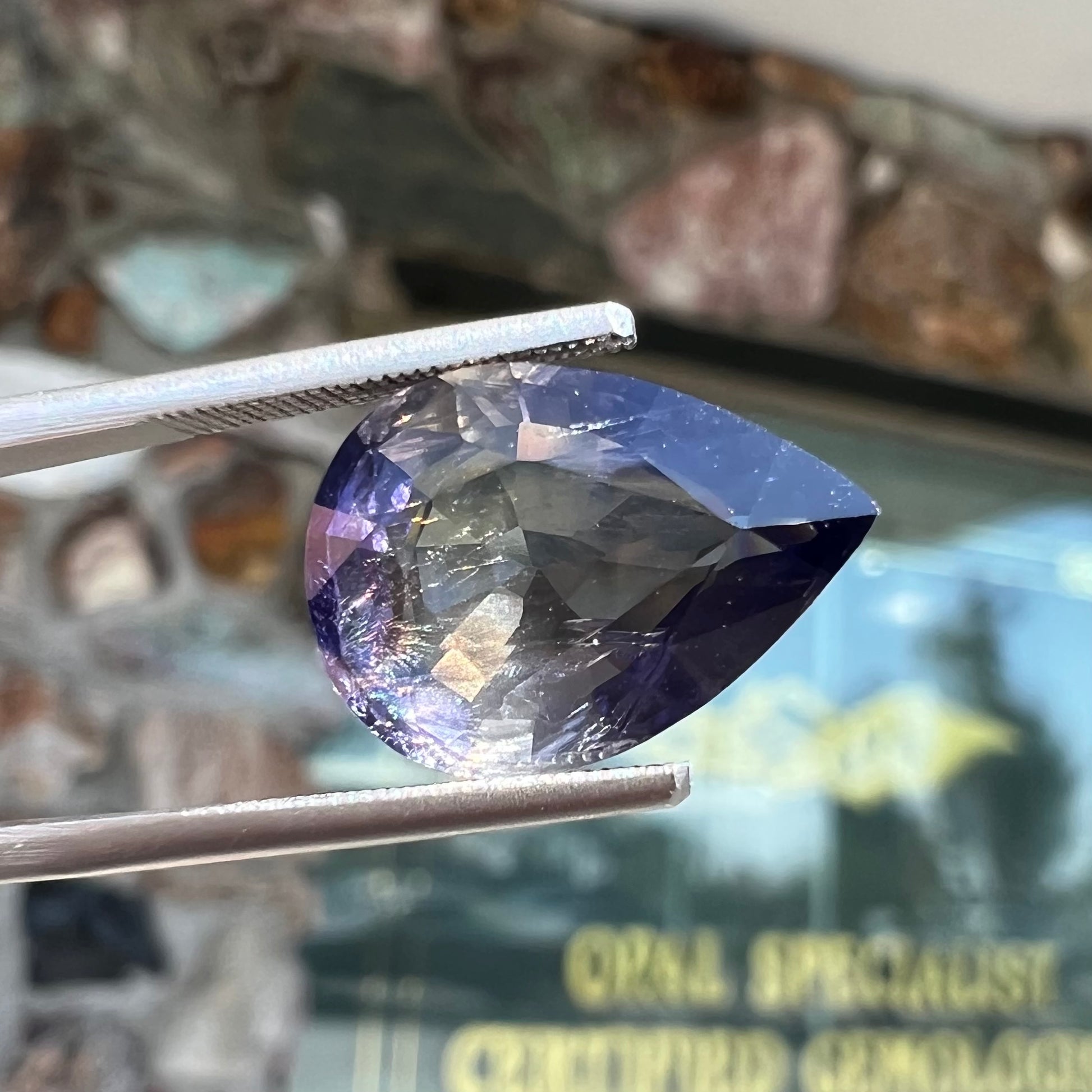 A loose, pear shaped bicolor iolite gemstone.  The stone shows violite purple and silver colors.