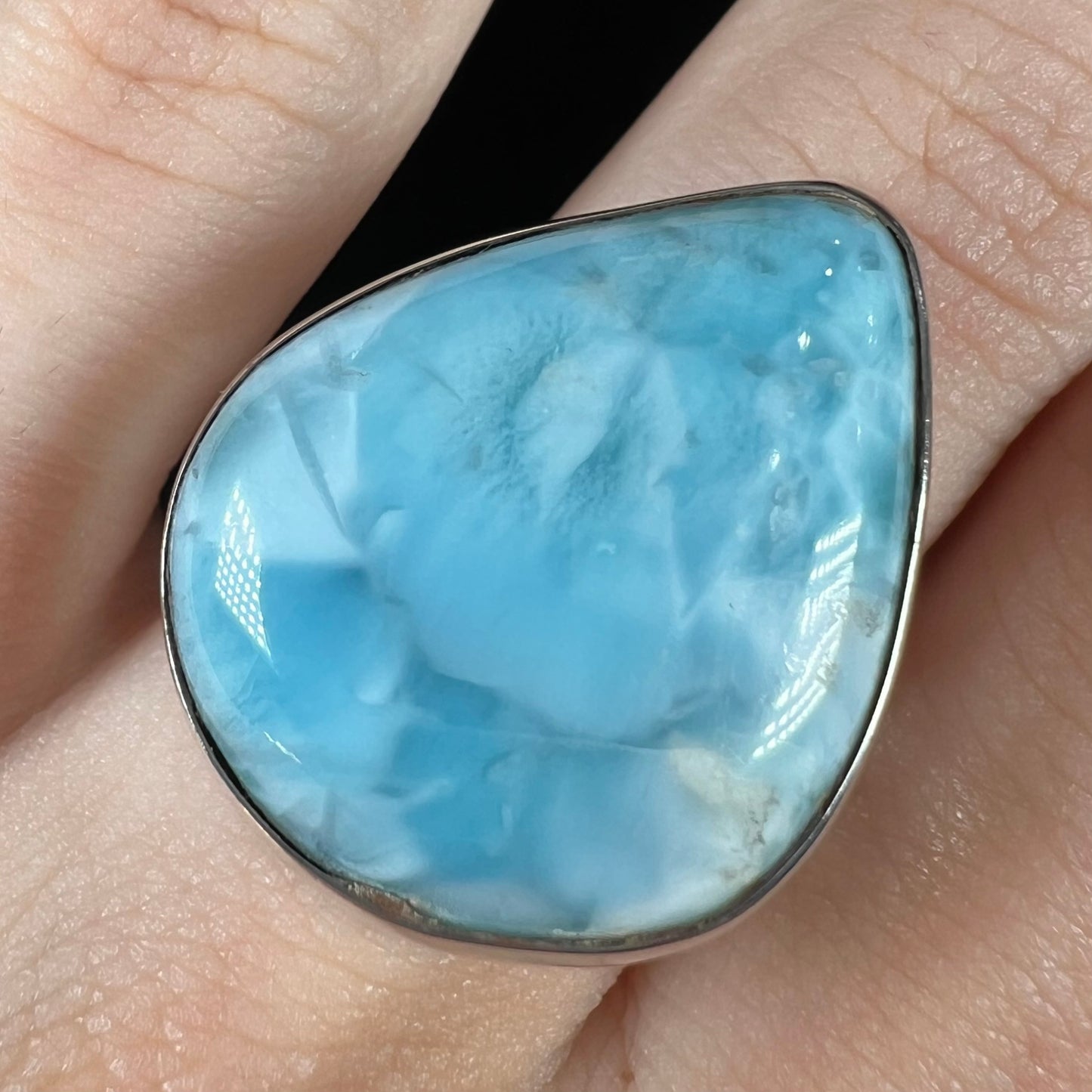 A ladies' large, pear shaped larimar solitaire ring in sterling silver.  The larimar stone measures an inch long.