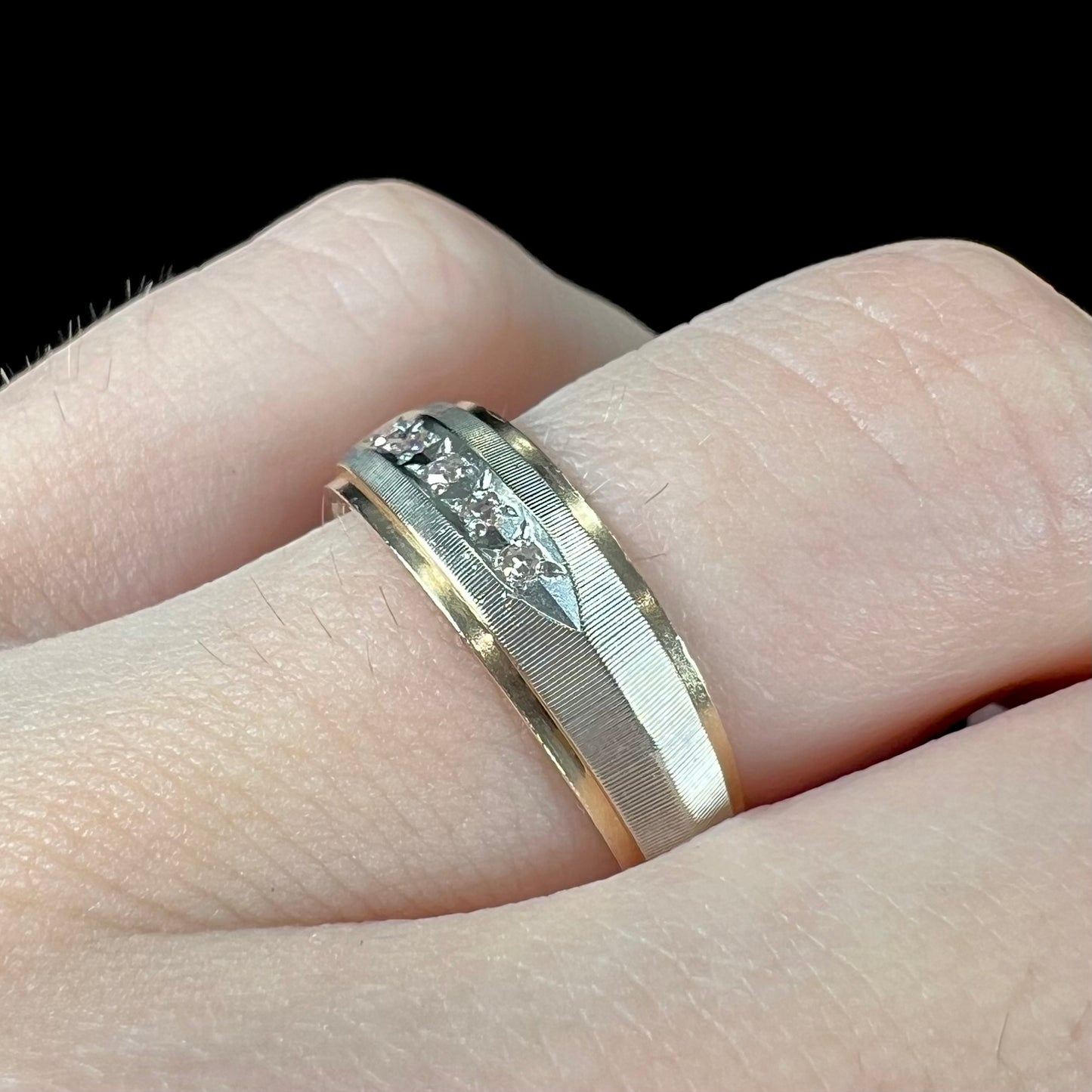 A unisex, two-tone white and yellow gold diamond wedding band.  The white gold is textured.