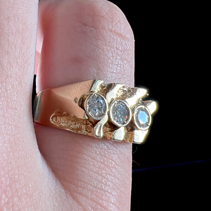 A men's yellow gold ring set with three round brilliant cut diamonds.  There are scratches along the shank.