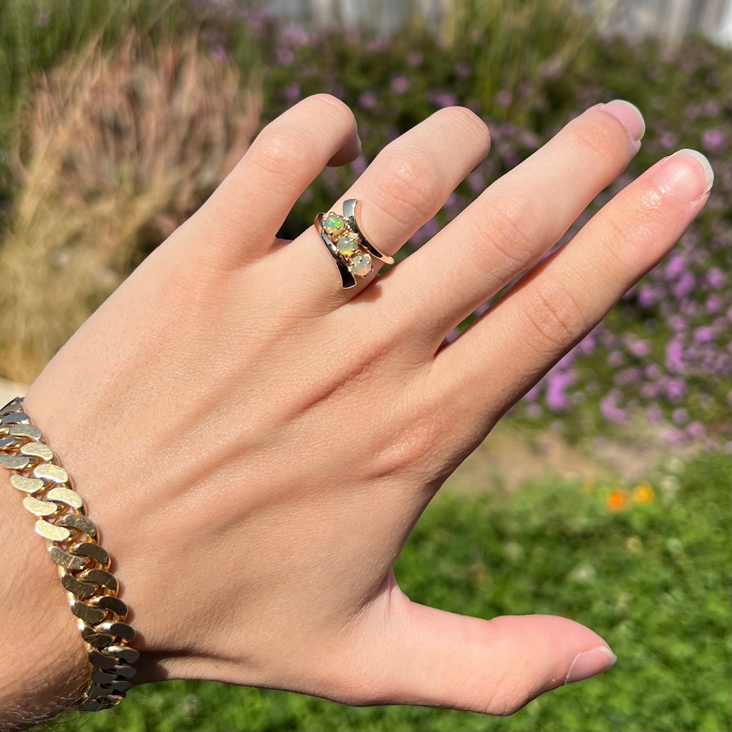 A yellow gold bypass shank ring mounted with three round cabochon cut Ethiopian fire opals.