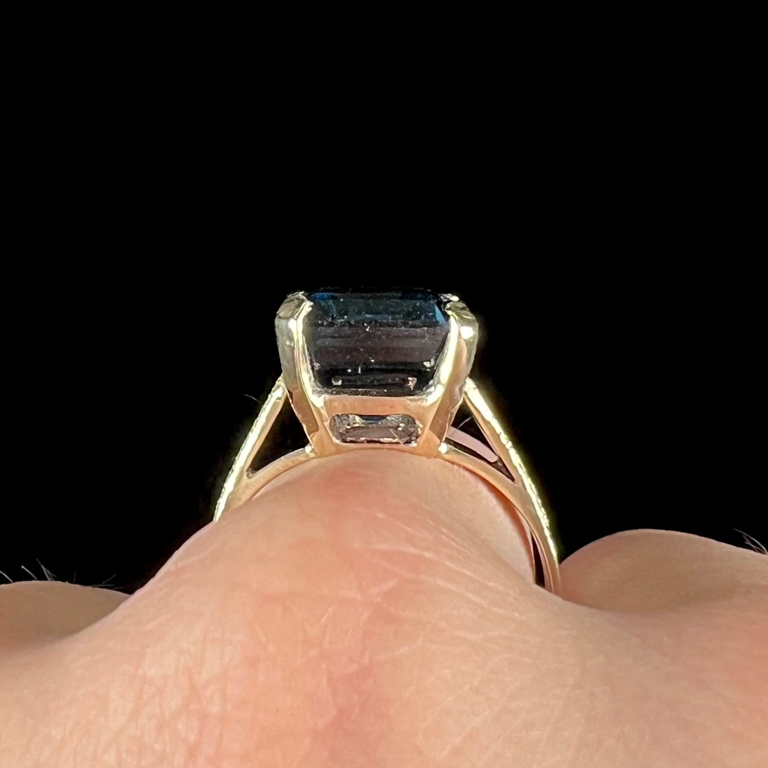 A ladies' yellow gold London blue topaz solitaire ring.  The ring is textured, and the topaz is emerald cut.