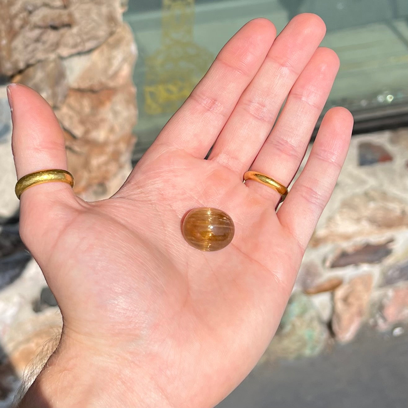 A loose, golden brown cat's eye dravite tourmaline gemstone.  The stone is cut into an oval shaped cabochon.