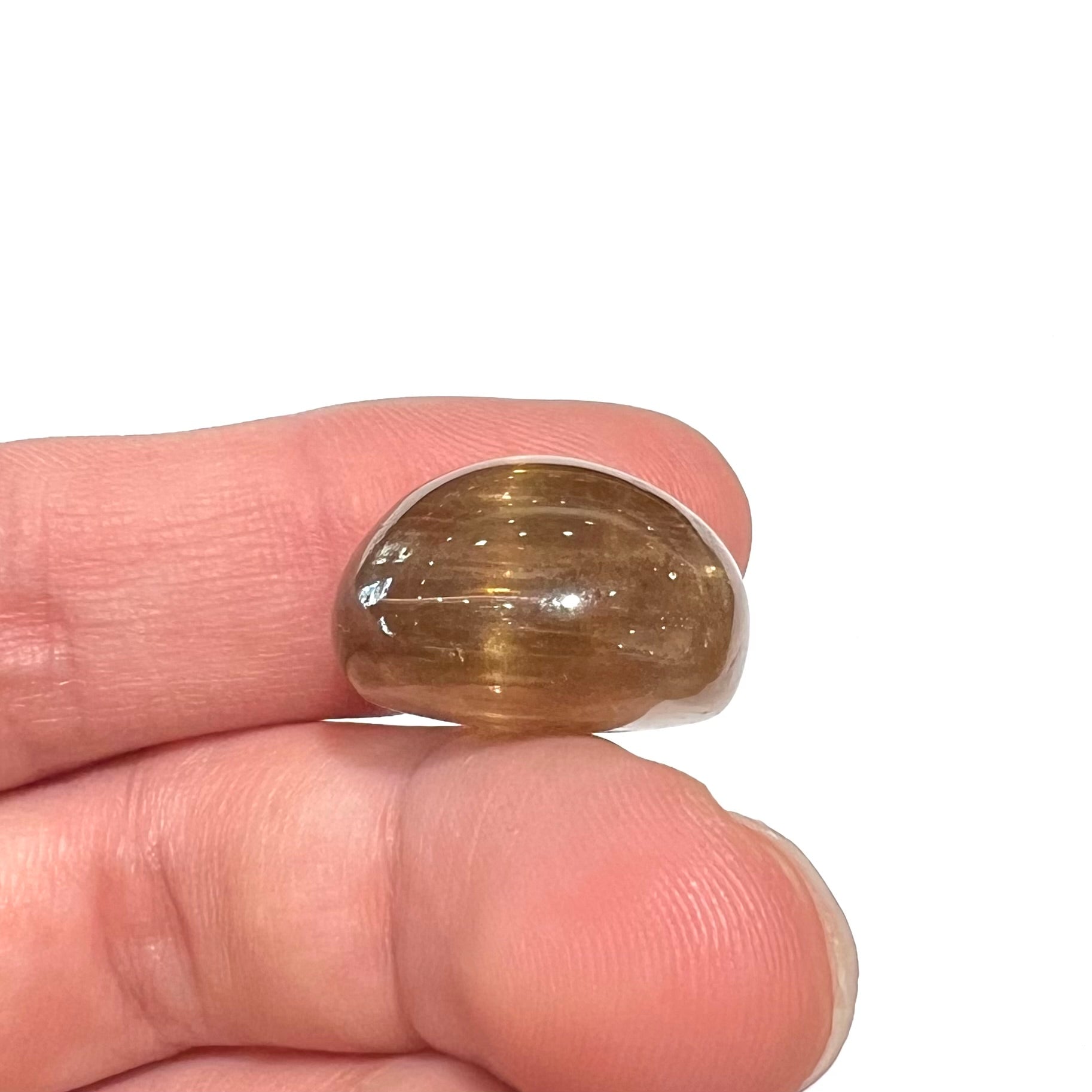 A loose, golden brown cat's eye dravite tourmaline gemstone.  The stone is cut into an oval shaped cabochon.