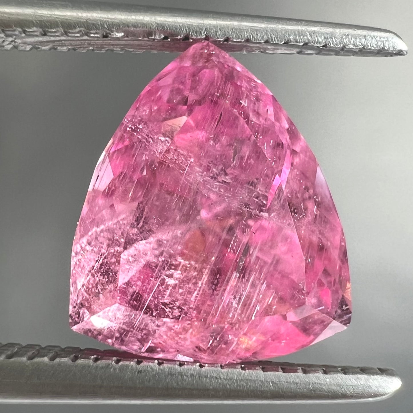 A loose, faceted trillion cut pink touramline gemstone.  The stone is a light bubblegum pink color.