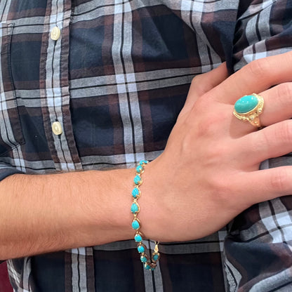 A ladies' yellow gold tennis style bracelet set with pear cabochon shaped natural Sleeping Beauty turquoise stones.