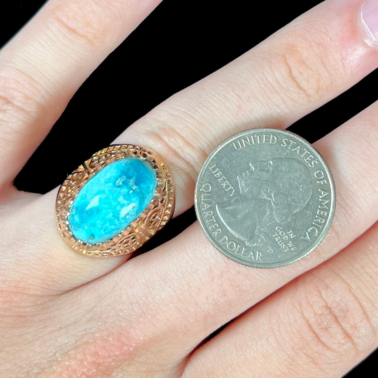 A yellow gold filigree style ring mounted with an oval Pilot Mountain turquoise stone.