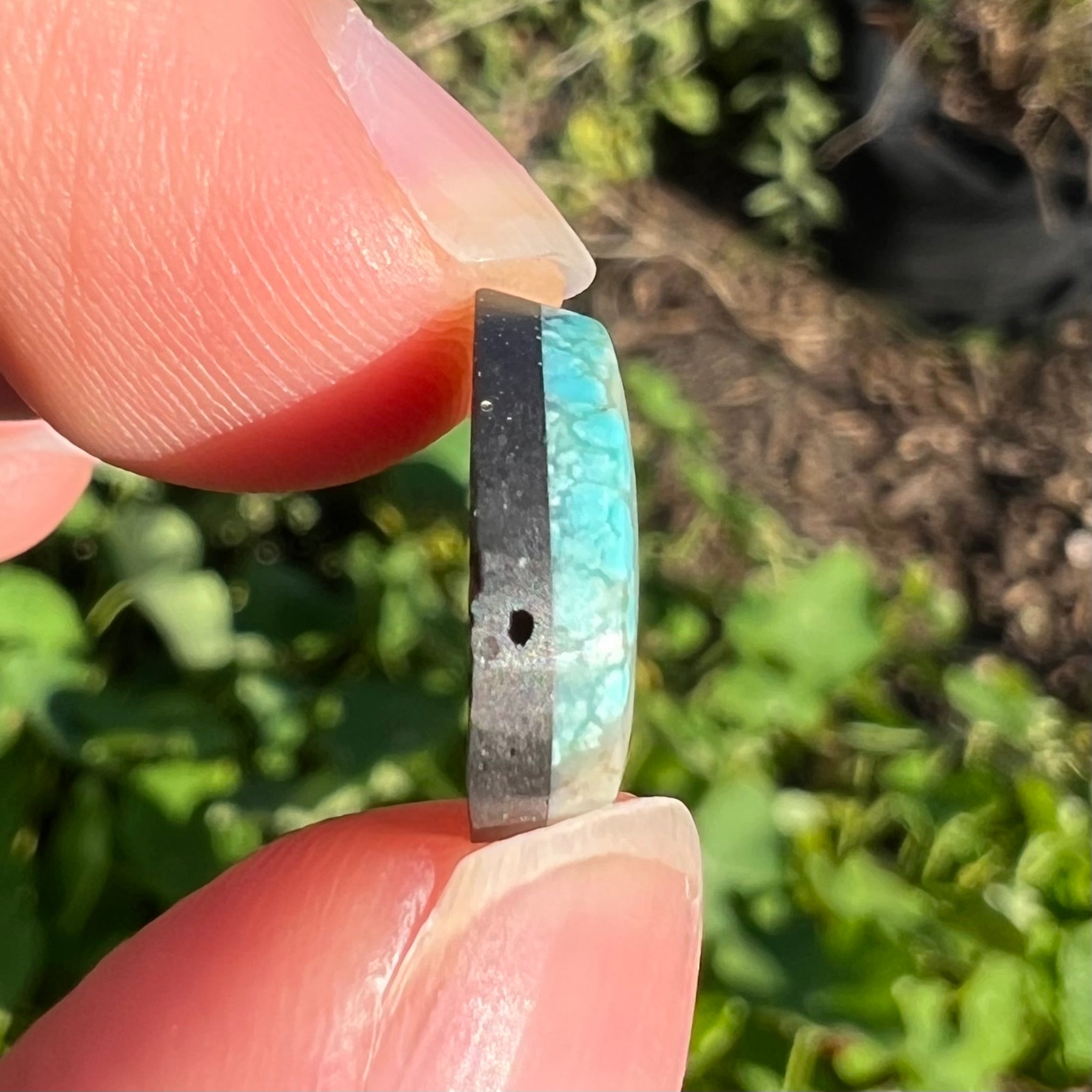 A loose, freeform pear shaped cabochon cut Valley Blue turquoise stone from Lander County, Nevada.  The stone is blue and green with quartz inclusions.