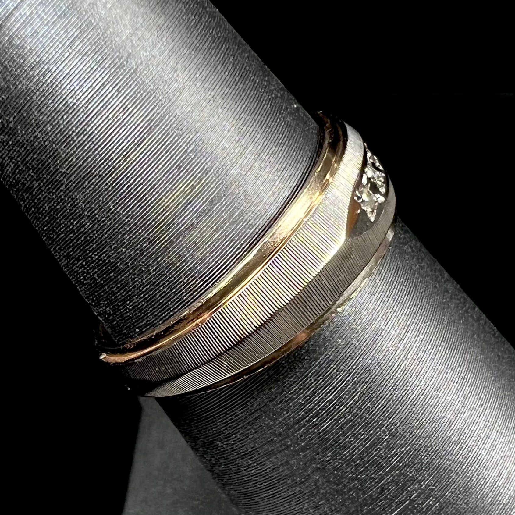 A unisex, two-tone white and yellow gold diamond wedding band.  The white gold is textured.