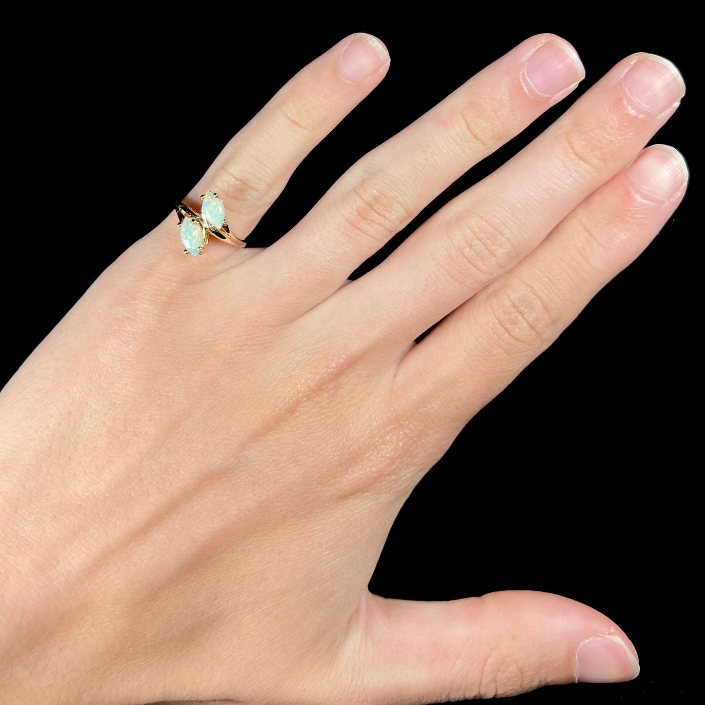 A yellow gold ring mounted with two prong-set marquise cut opal cabochons.