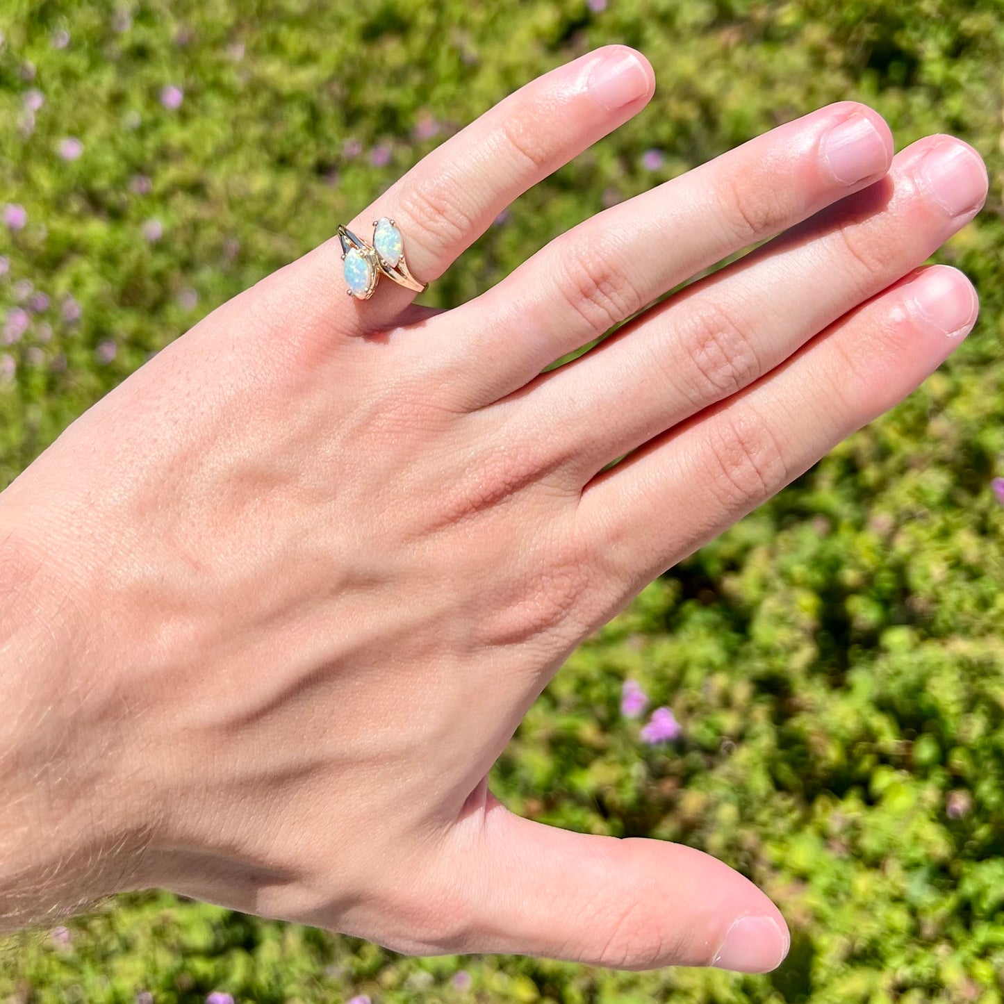 A yellow gold ring mounted with two prong-set marquise cut opal cabochons.