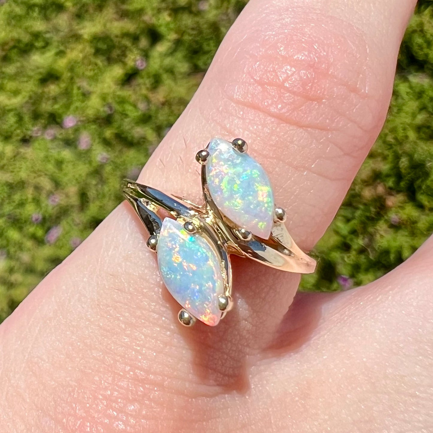 A yellow gold ring mounted with two prong-set marquise cut opal cabochons.