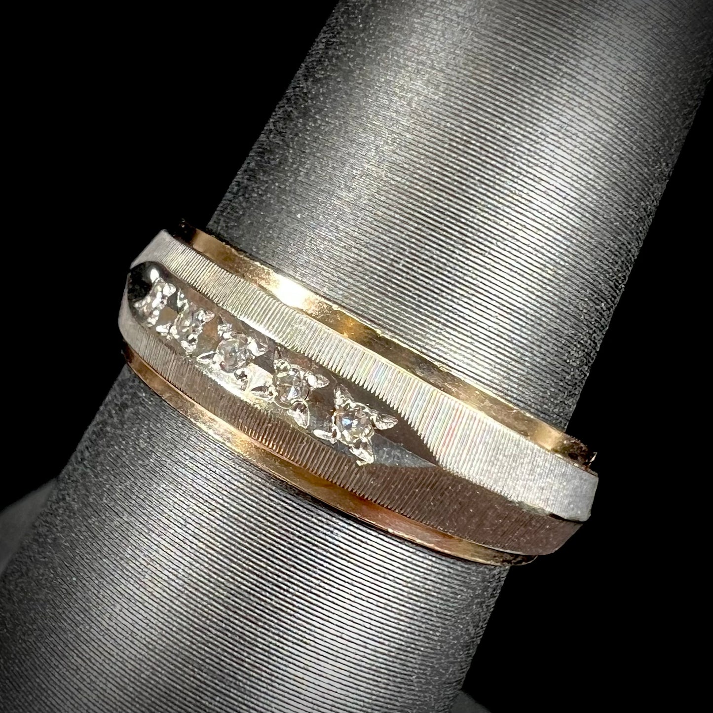 A unisex, two-tone white and yellow gold diamond wedding band.  The white gold is textured.