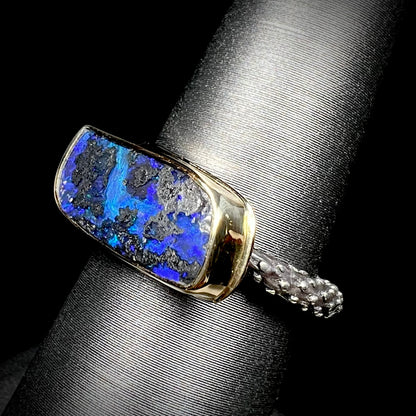 A two-tone sterling silver and 18k gold ring set with a blue boulder opal stone.  The shank is textured.