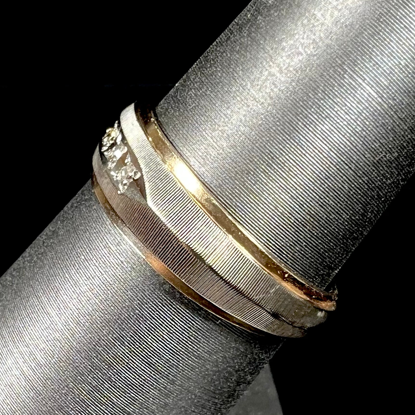 A unisex, two-tone white and yellow gold diamond wedding band.  The white gold is textured.