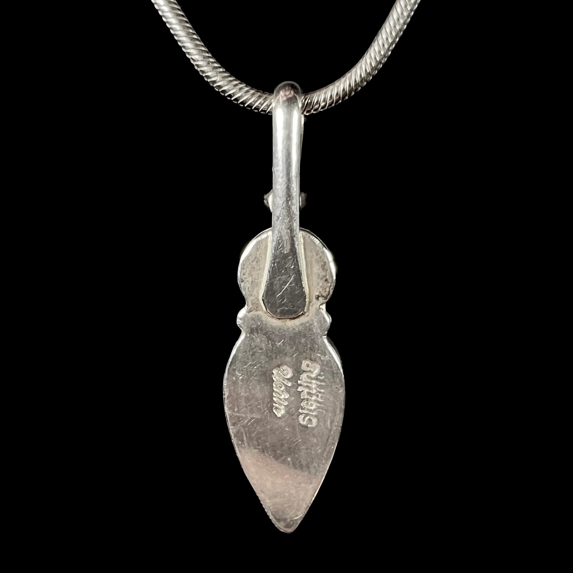 A sterling silver necklace shaped like a child, mounted with an opal doublet, a ruby, and a blue piece of glass.