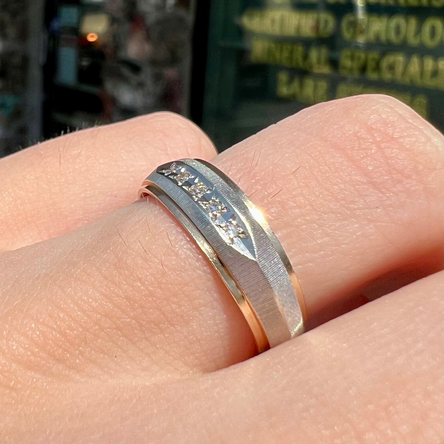 A unisex, two-tone white and yellow gold diamond wedding band.  The white gold is textured.