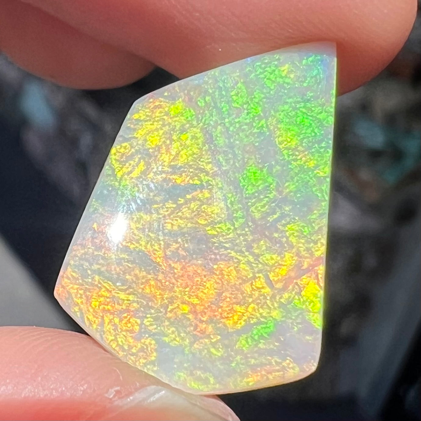 A large, white opal stone from Andamooka, Australia.  The stone shines soft colors of orange, yellow, and green.