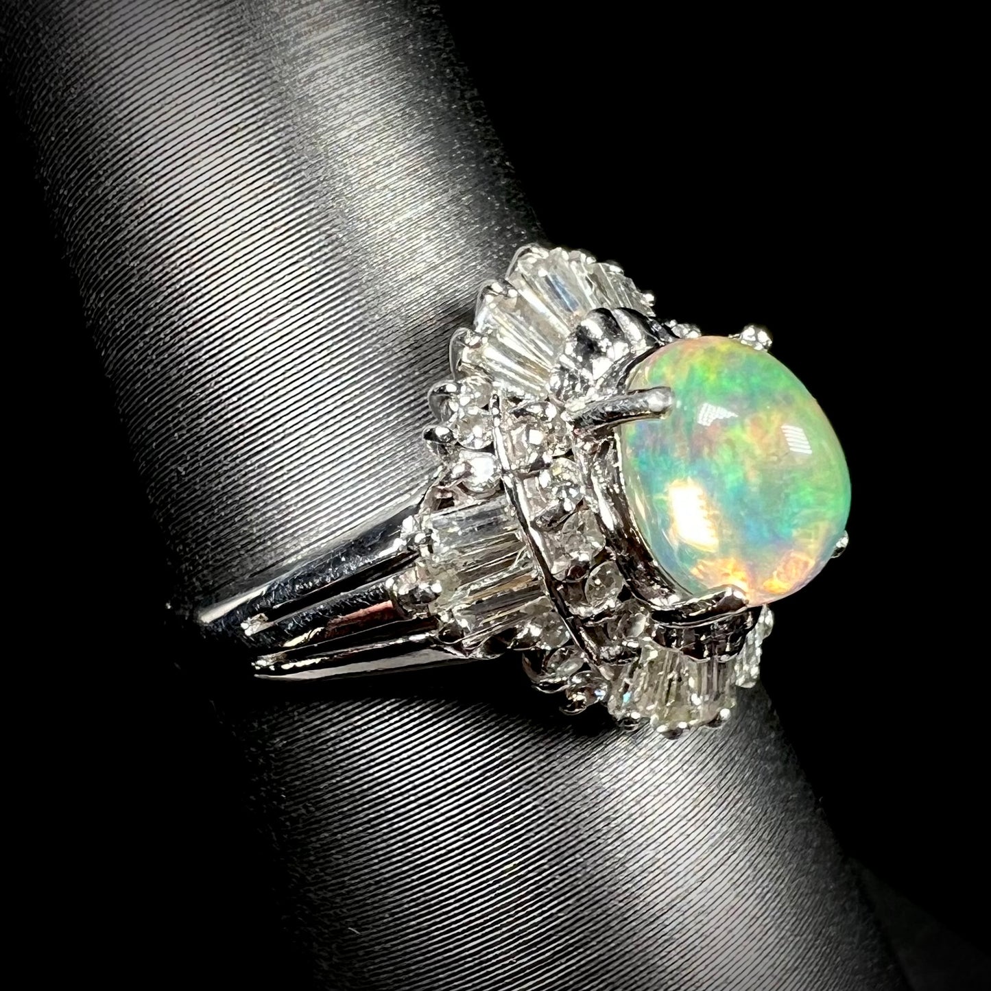 A platinum ring mounted with a Mexican fire opal and baguette cut diamond accents.