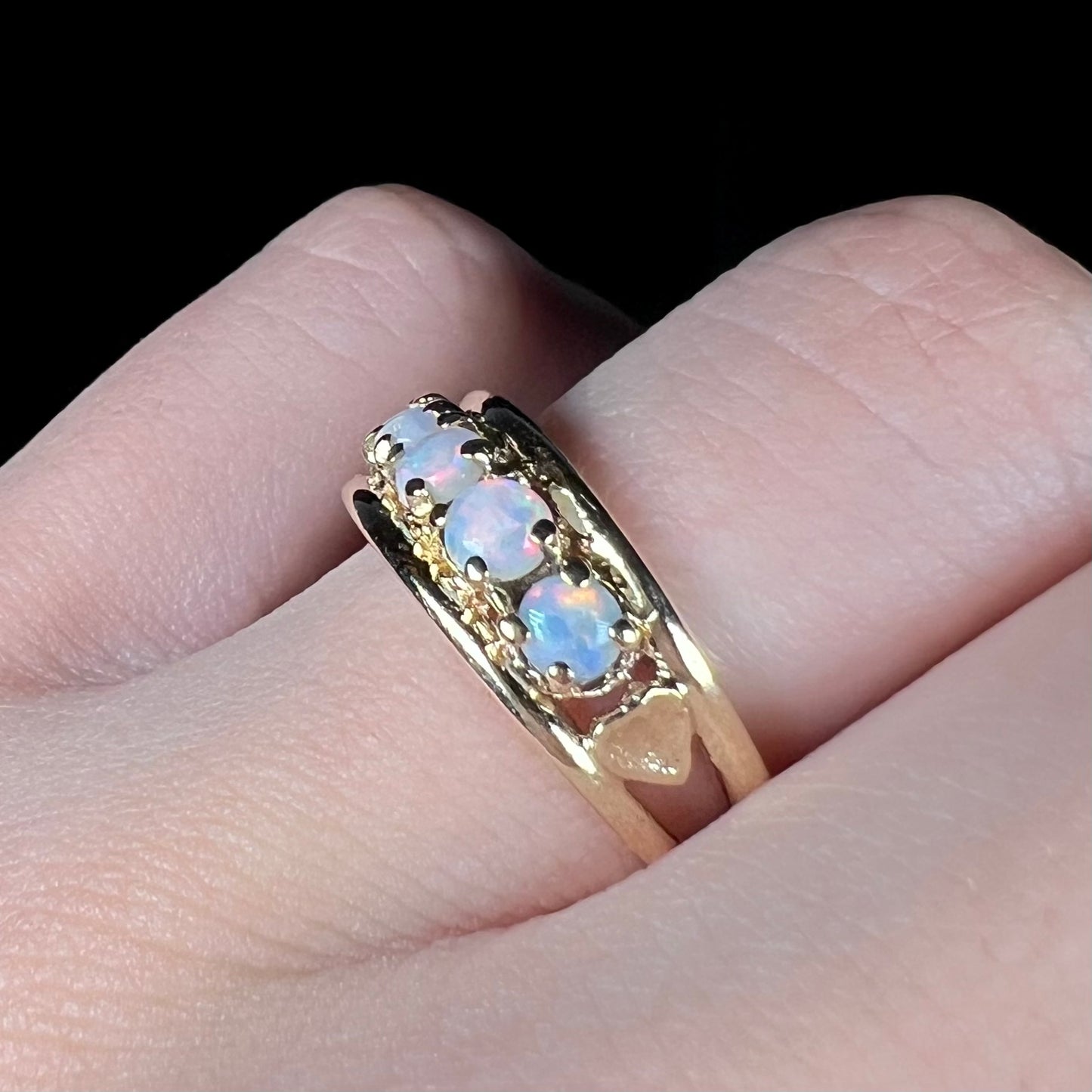 A yellow gold band set with five round cabochon cut opals and heart design accents.