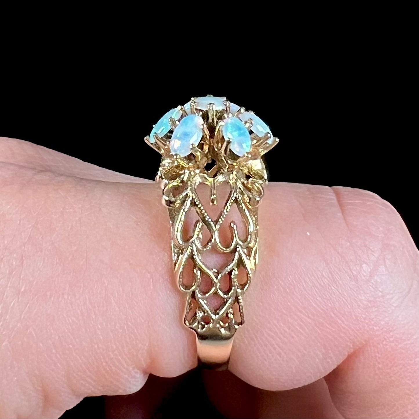 A vintage, 1950's style opal cluster ring cast in yellow gold with a heart shaped filigree design.