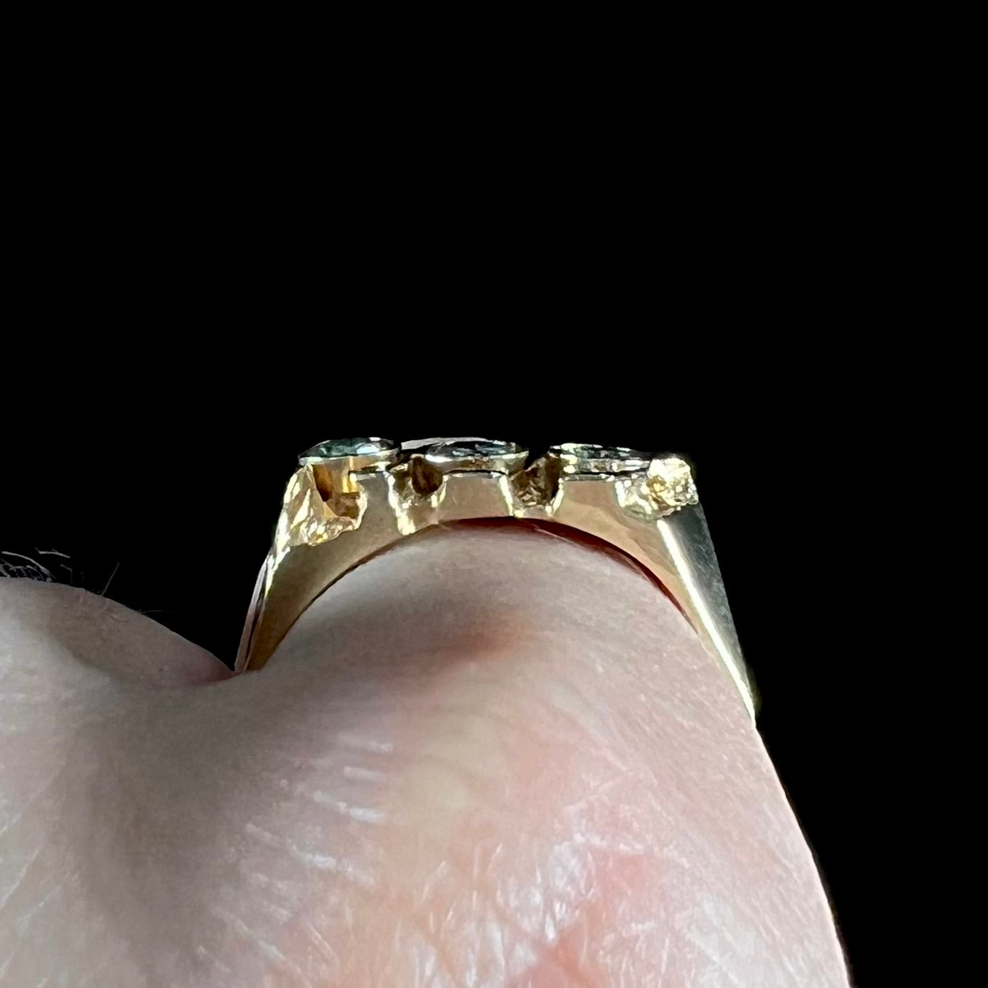 A men's yellow gold ring set with three round brilliant cut diamonds.  There are scratches along the shank.