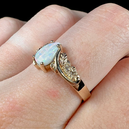 A ladies' two-tone yellow and rose Black Hills gold opal and diamond ring.  The opal is a pear shaped cabochon.