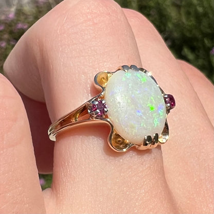 A 1920's Art Nouveau opal and pink sapphire ring.   The ring is yellow gold and palladium.  The opal is green and purple.