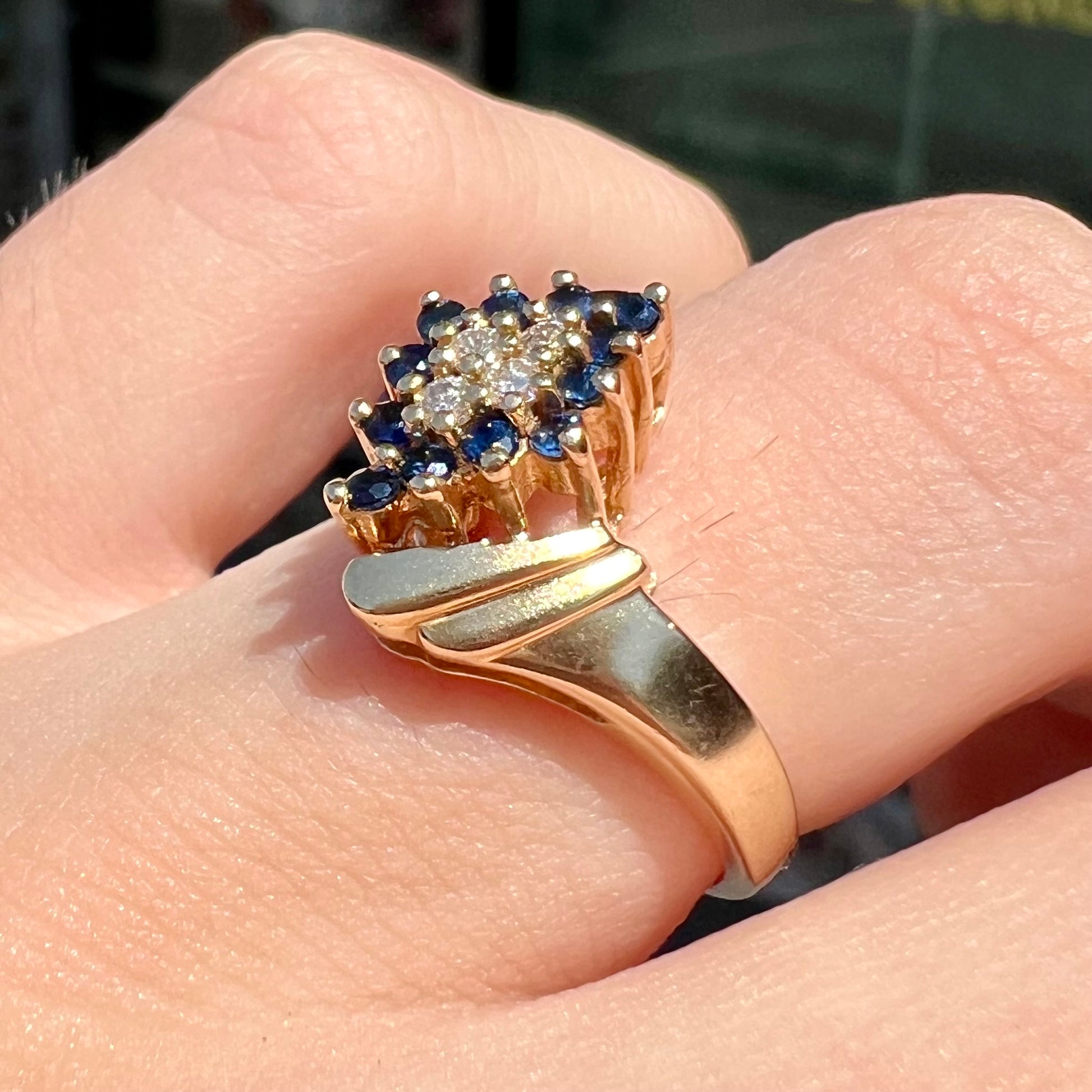 An estate, yellow gold ladies' cluster ring mounted with four round diamonds and twelve round blue sapphires.