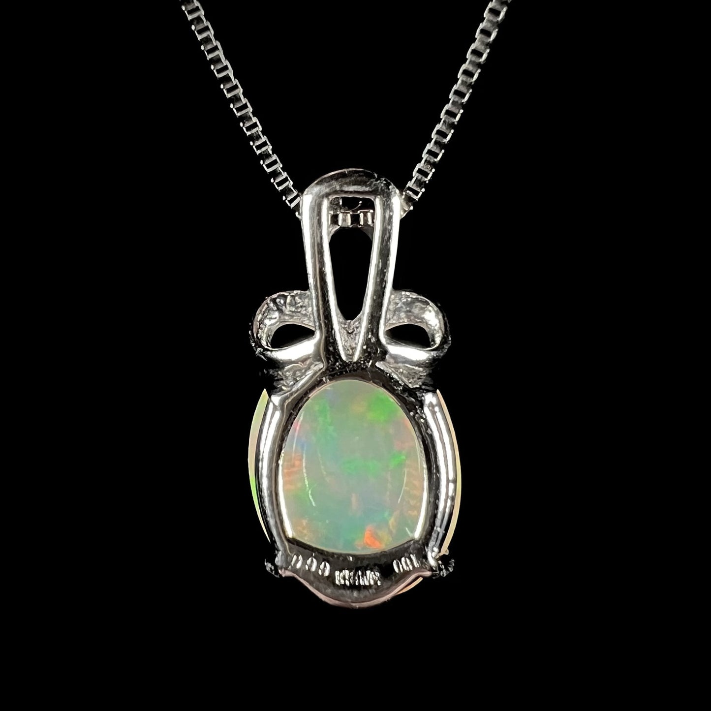 An oval cut Ethiopian opal mounted in a diamond-accented, 18 karat white gold pendant on a box chain.