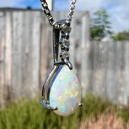 A platinum drop pendant mounted with three diamond accents and a pear shaped opal.