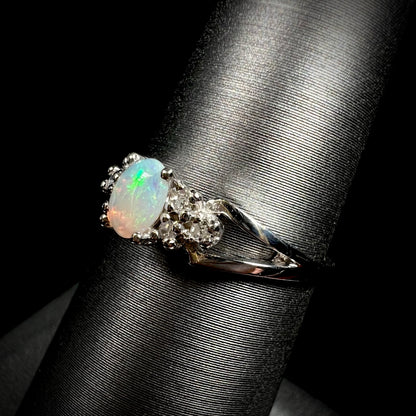 A ladies' white gold opal ring mounted with round diamond accents.