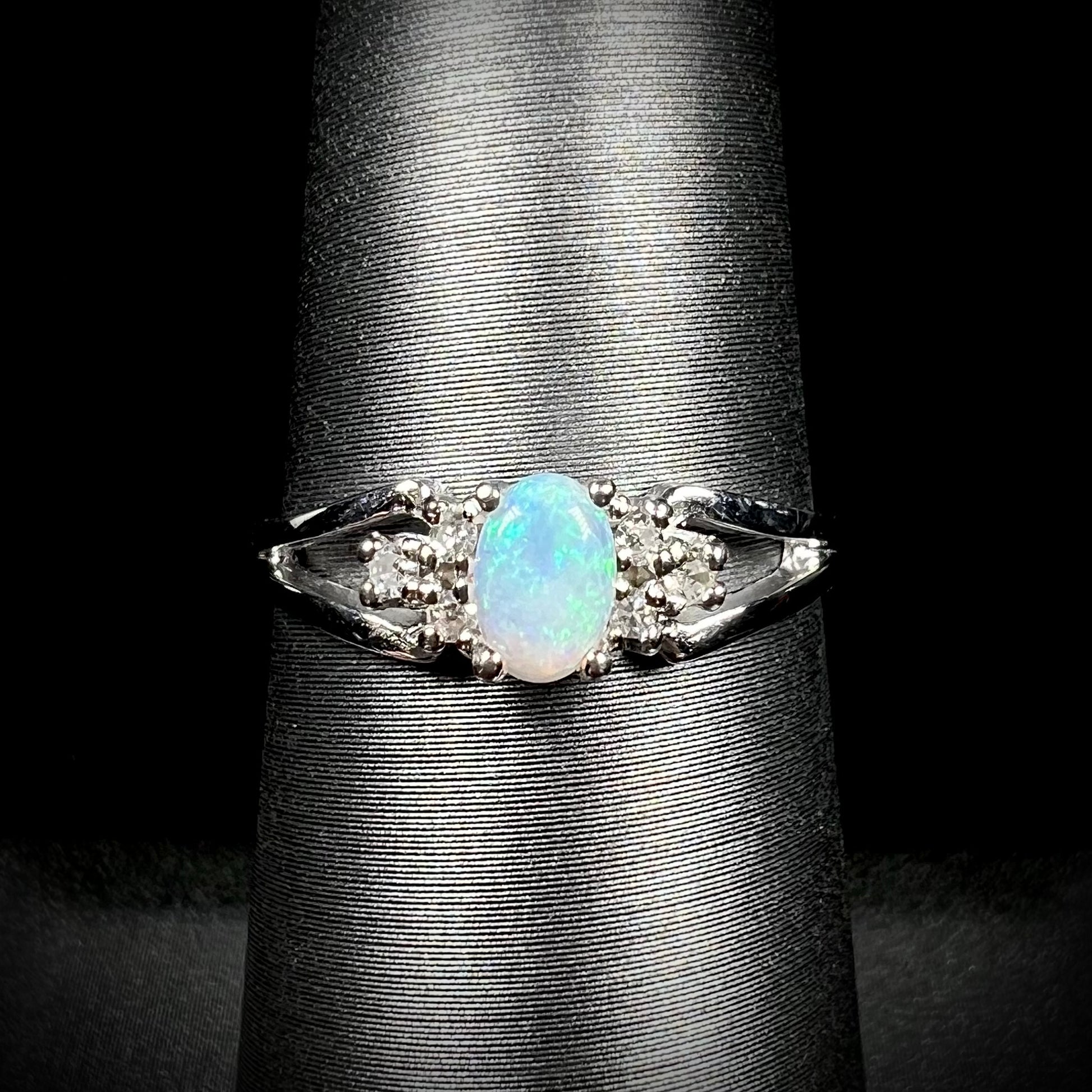 A ladies' white gold opal ring mounted with round diamond accents.