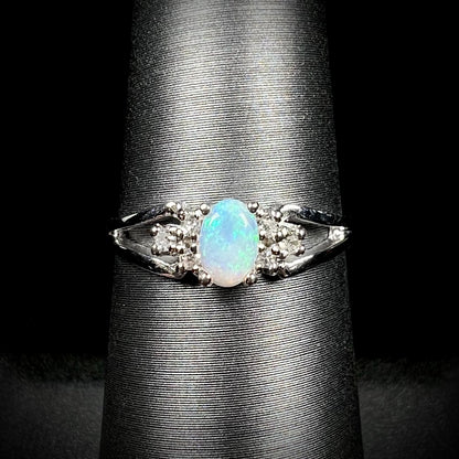 A ladies' white gold opal ring mounted with round diamond accents.