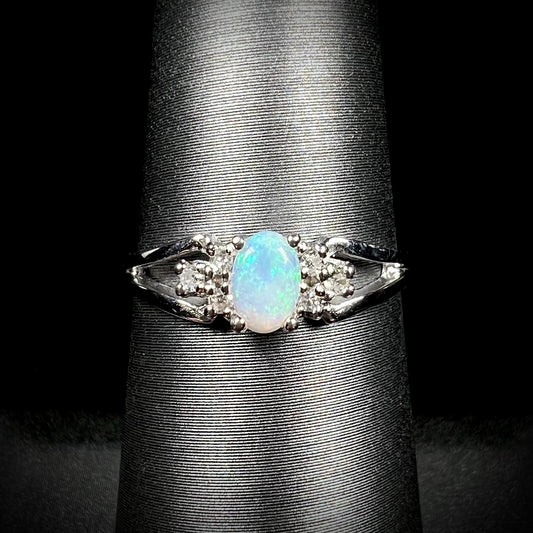 A ladies' white gold opal ring mounted with round diamond accents.