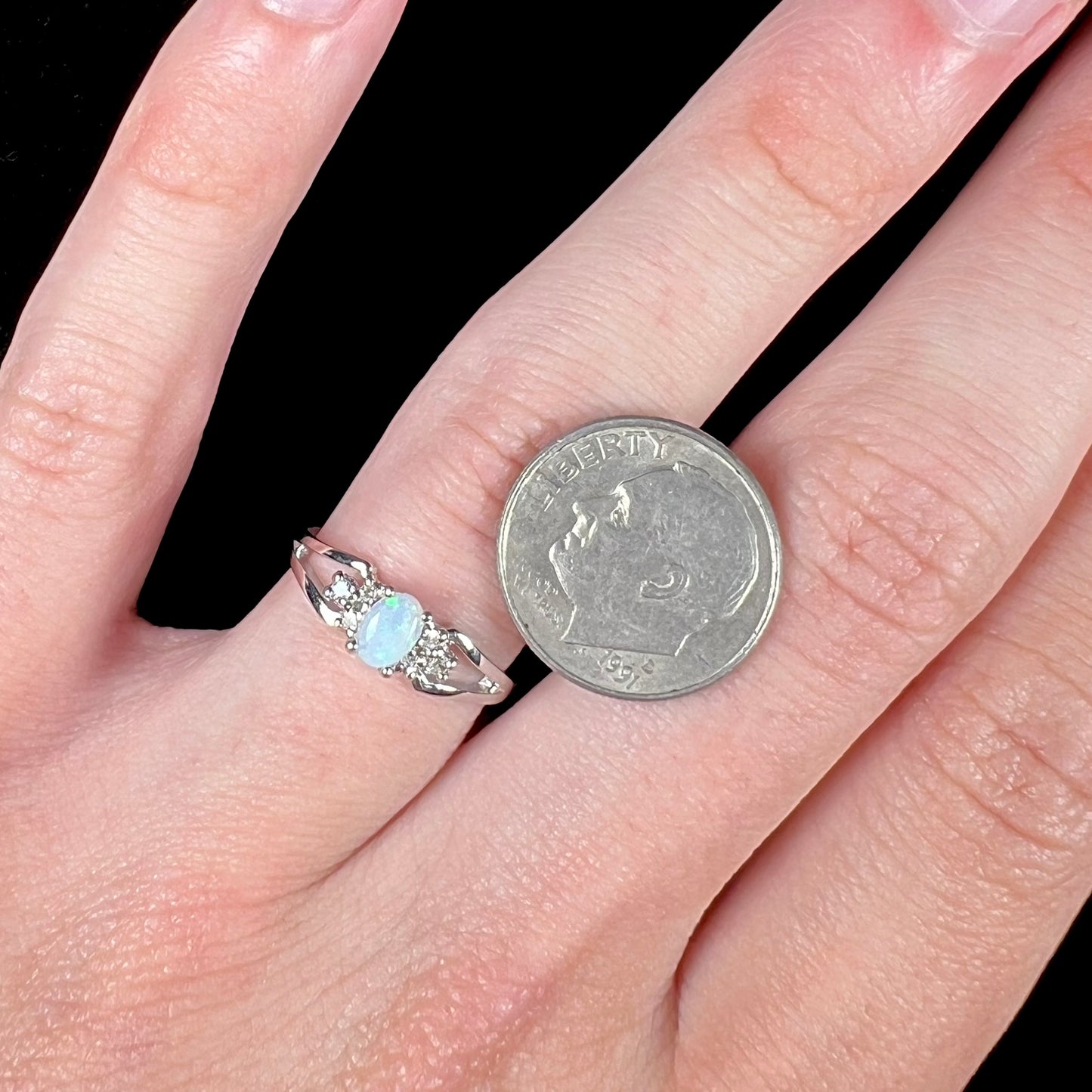 A ladies' white gold opal ring mounted with round diamond accents.