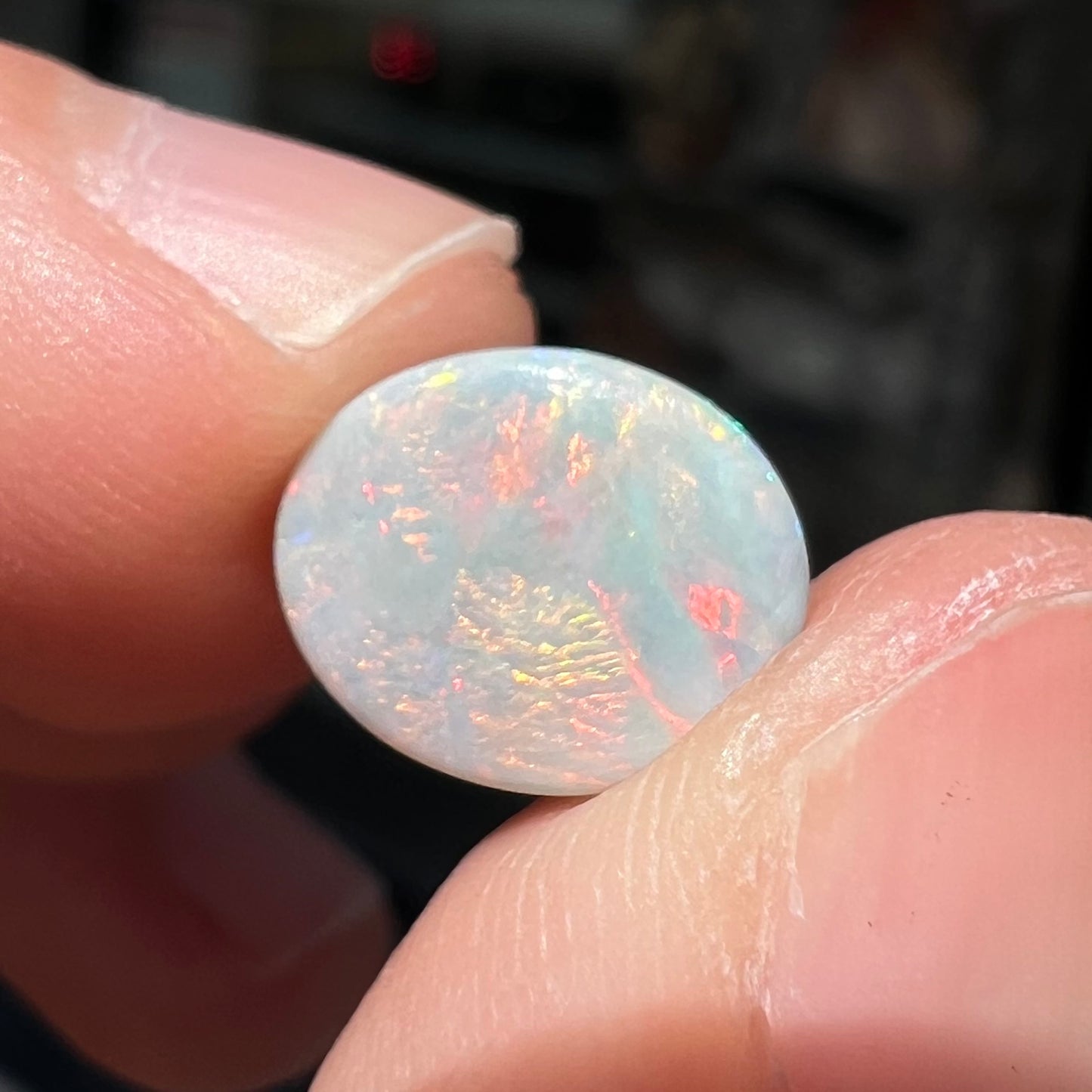 A loose, oval cabochon cut Lightning Ridge light opal stone.