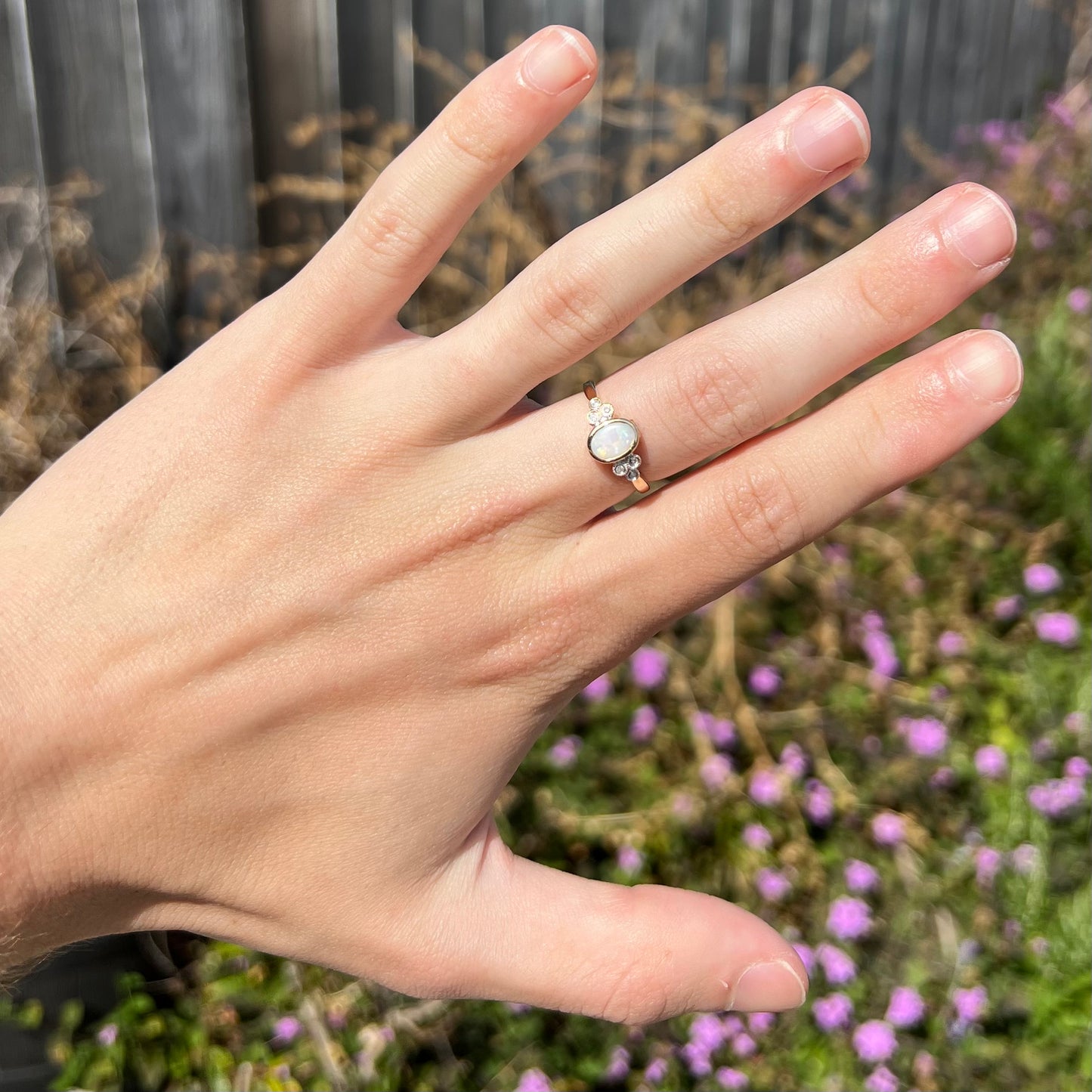 A ladies' yellow gold opal ring.  Three diamonds are set on each side of the opal.  Two rubies are set under the opal.