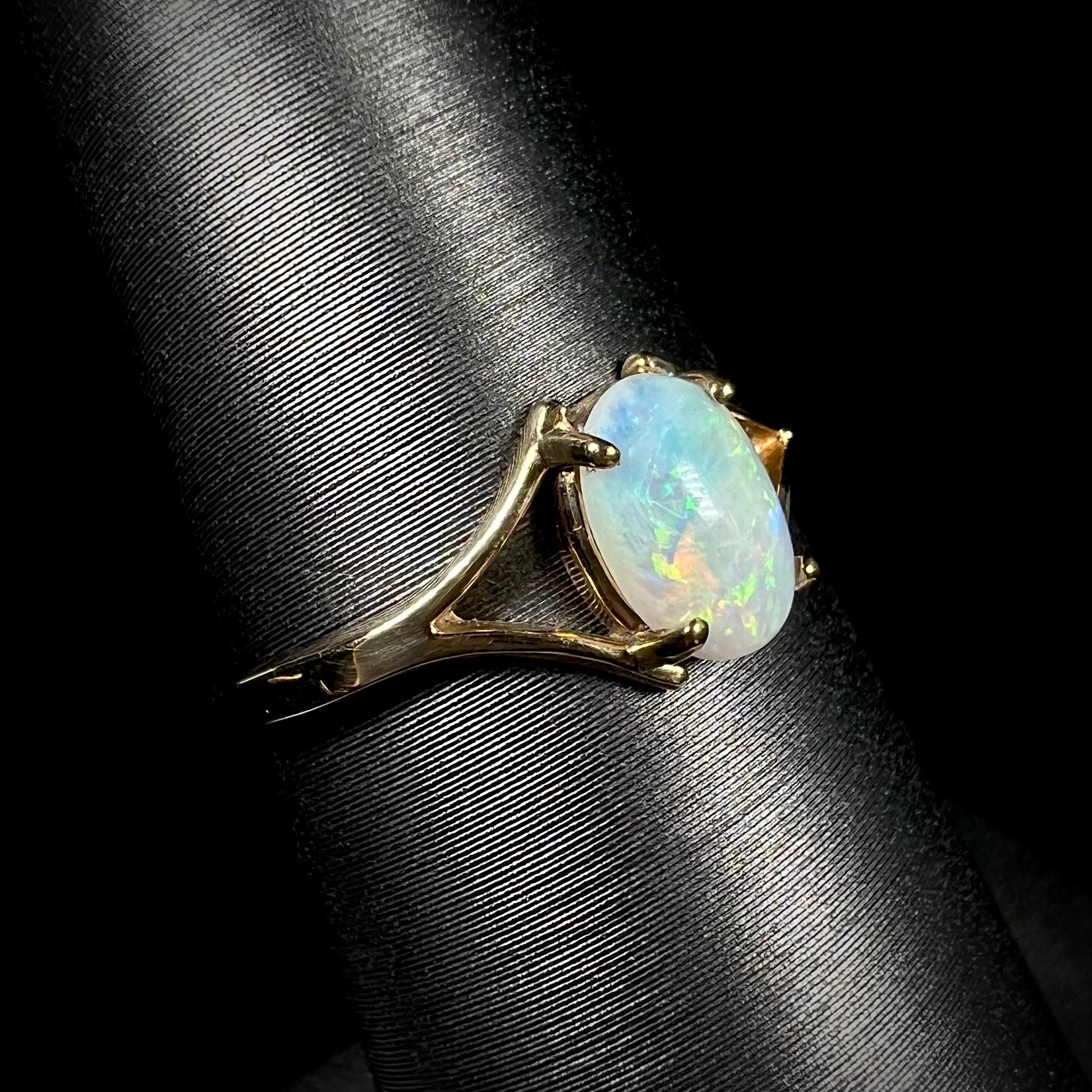 A ladies' simple opal solitaire ring.  The ring is yellow gold with a split shank.