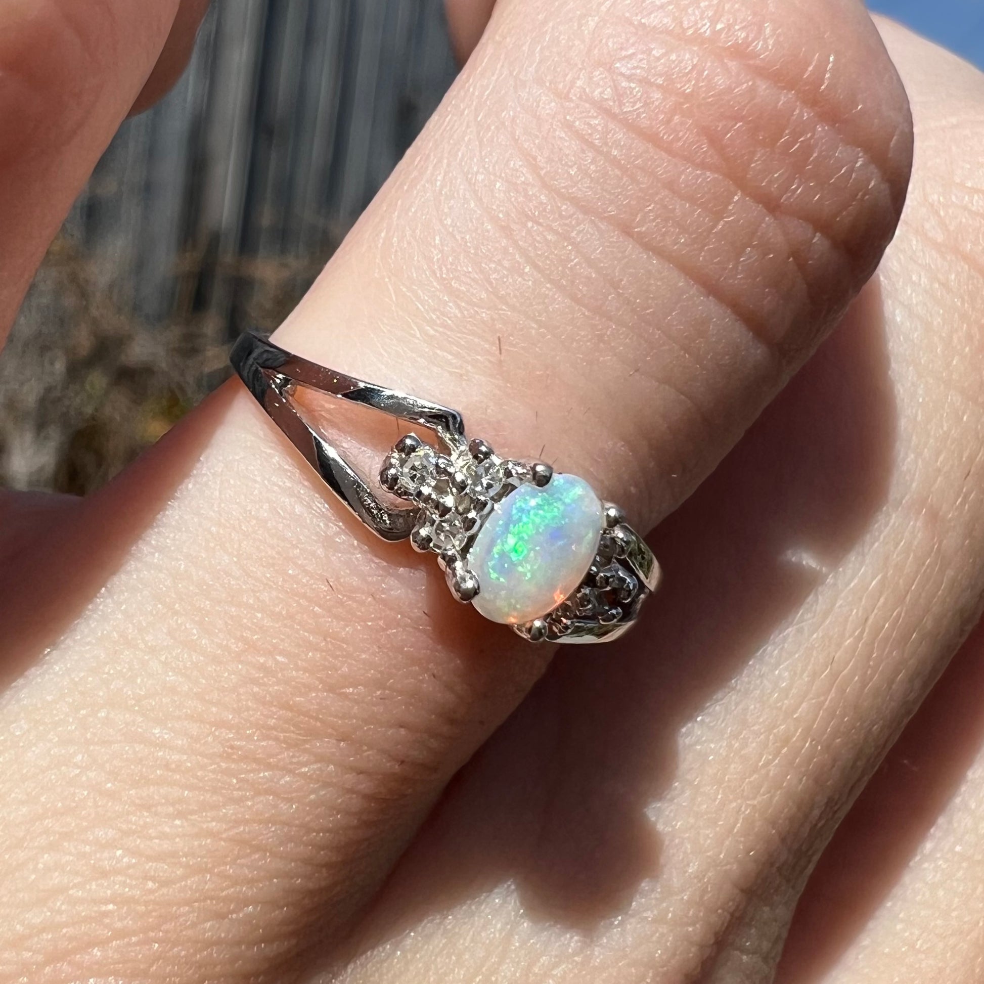 A ladies' white gold opal ring mounted with round diamond accents.