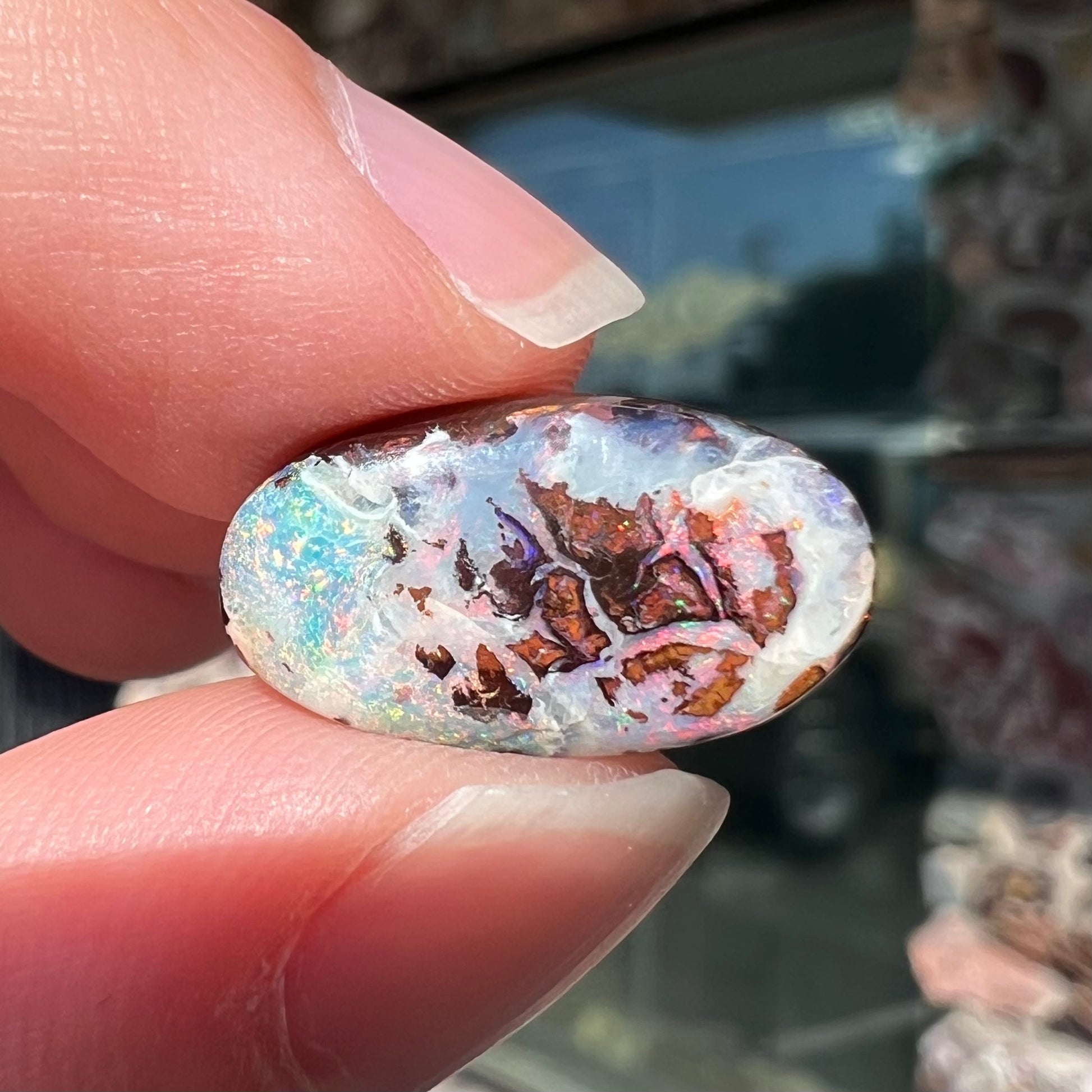 An oval cabochon cut boulder opal stone from Koroit, Australia.  The opal has a white body tone.