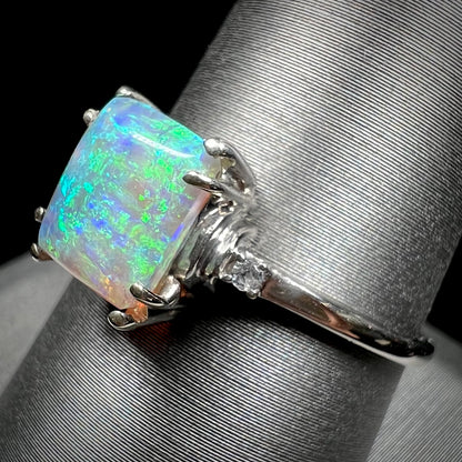 A ladies' white gold ring set with a rectangle cut black opal stone with round white sapphire accent stones.