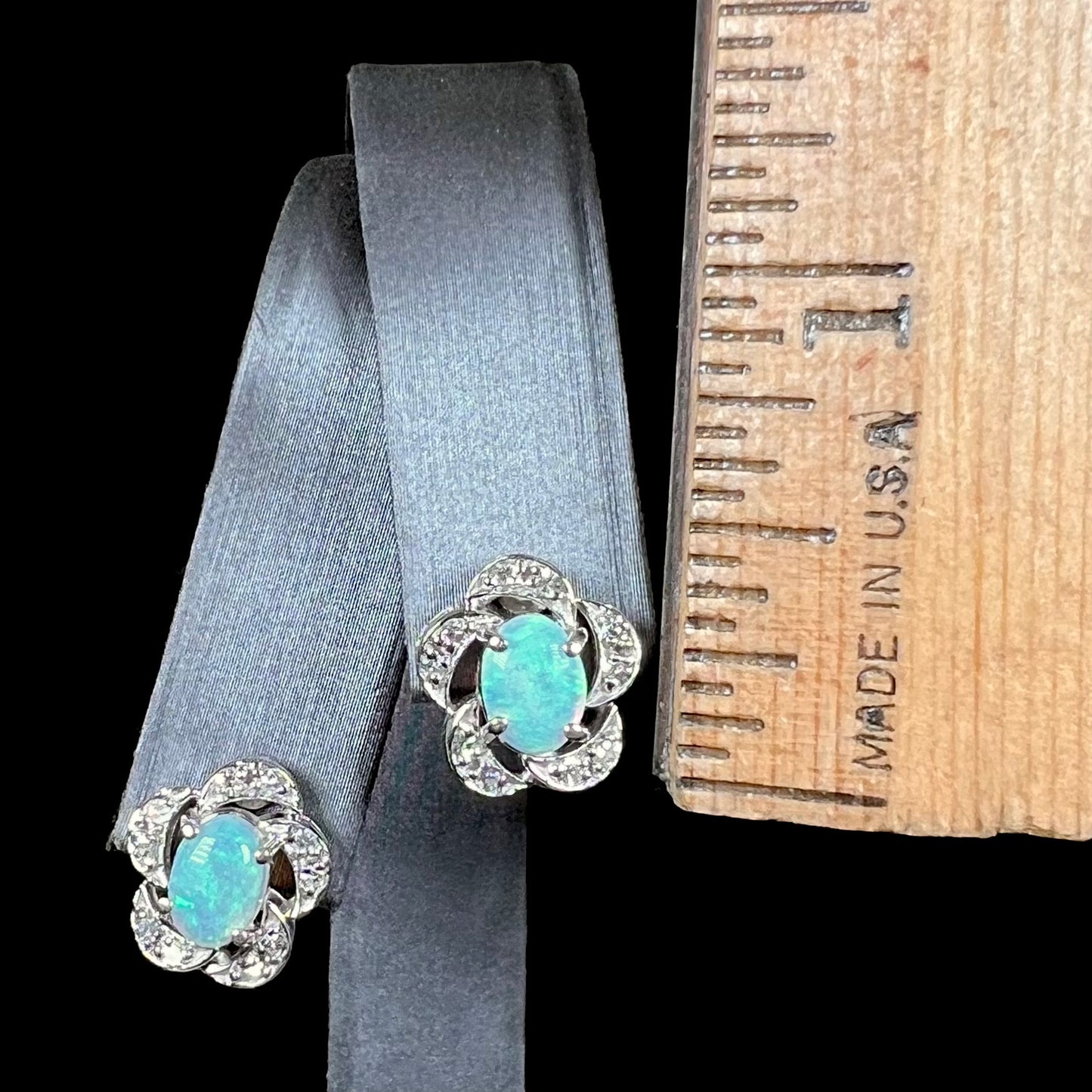 A pair of white gold flower stud earrings with diamonds mounted in the petals and opals set in the center.