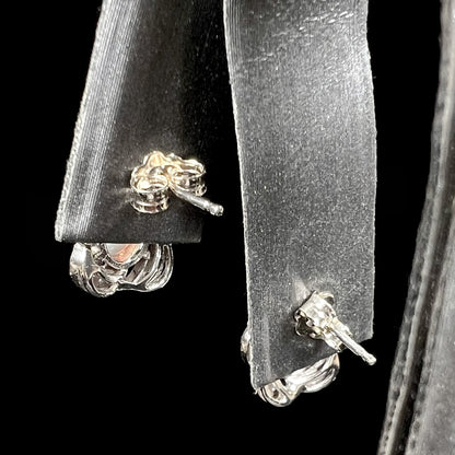 A pair of white gold flower stud earrings with diamonds mounted in the petals and opals set in the center.