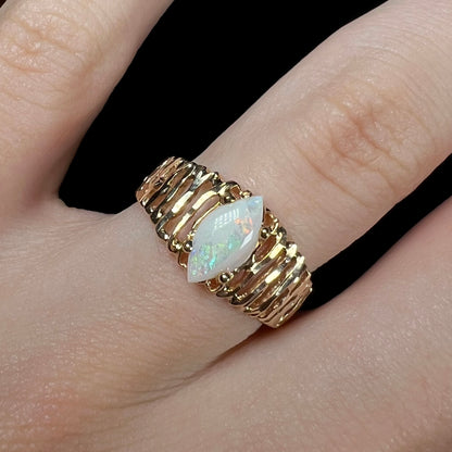 A ladies' yellow gold diamond-cut ring prong set with a natural, marquise cut white opal stone.