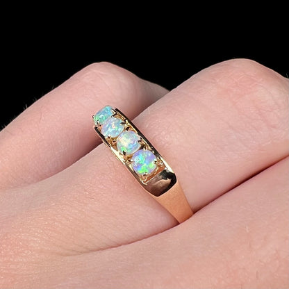 An 18 karat yellow gold line-style filigree ring mounted with five round, cabochon cut Australian crystal opals.