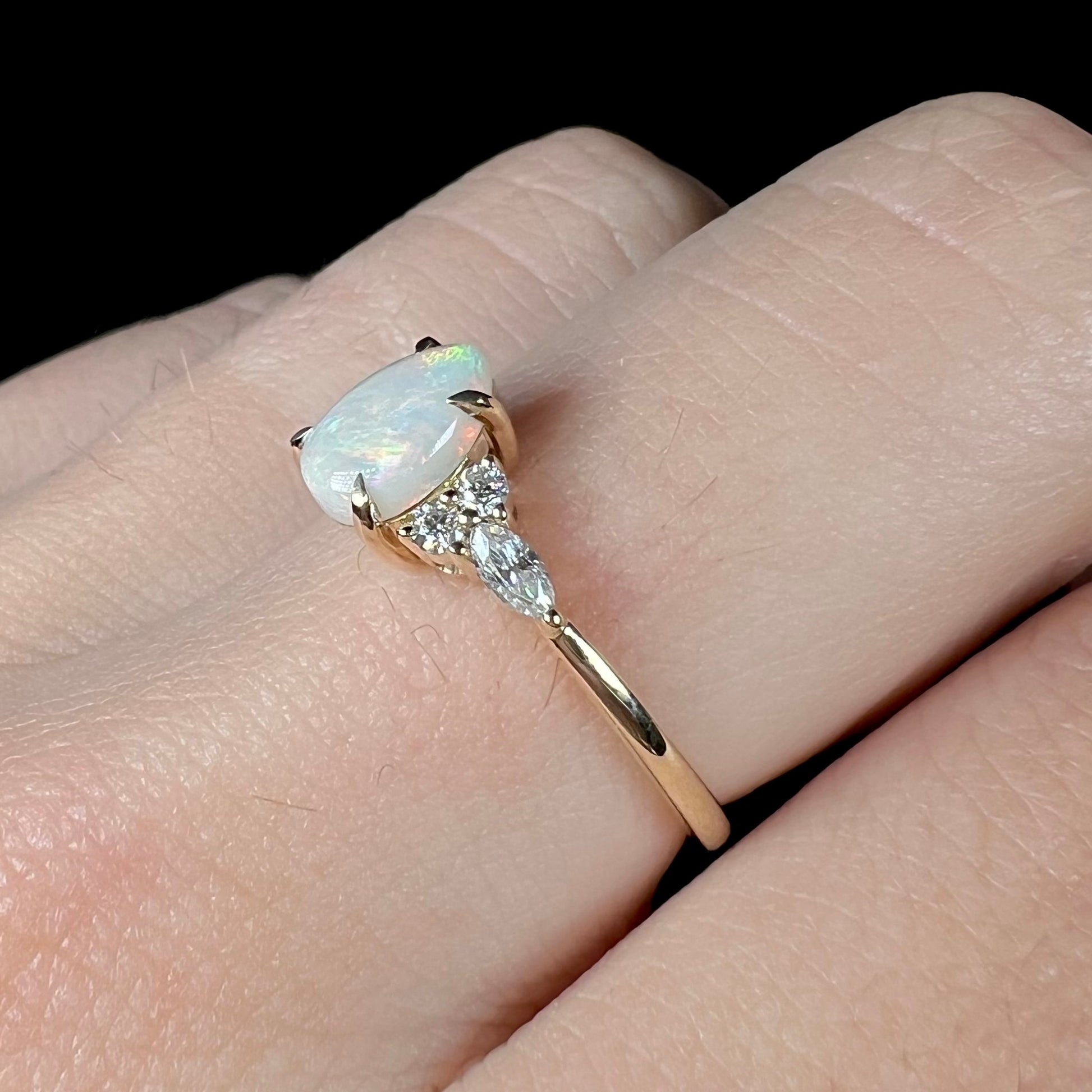 A dainty, pear shaped opal ring mounted in yellow gold with moissanite accents.