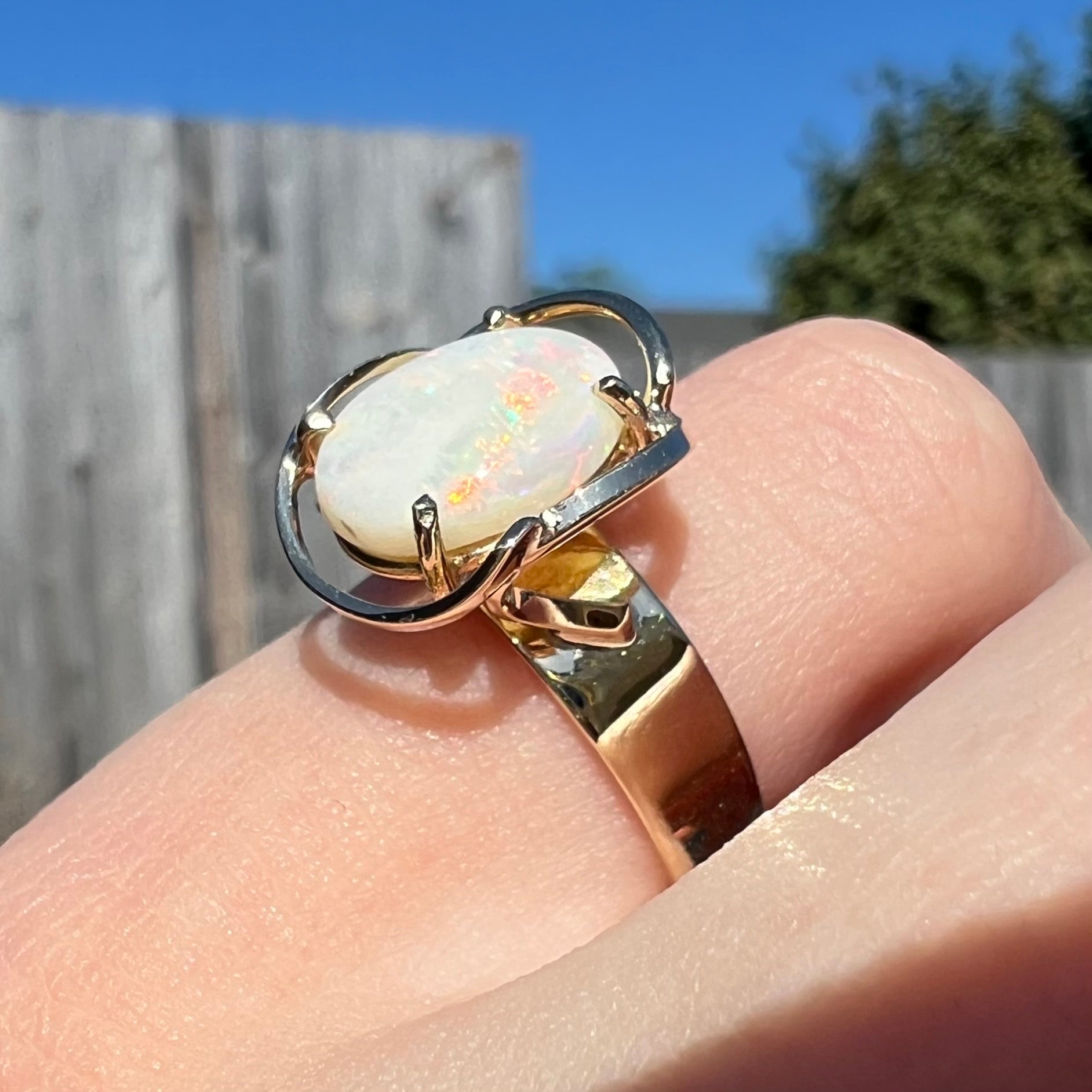 A yellow gold solitaire ring mounted with an oval cut Australian white opal.