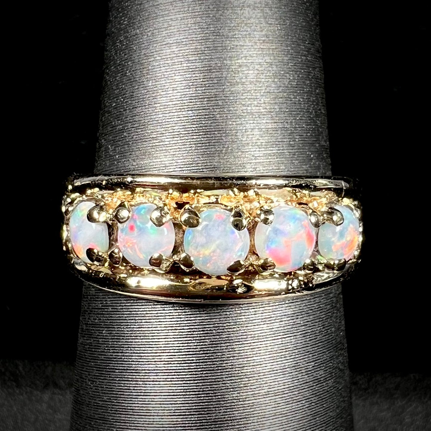 A yellow gold band set with five round cabochon cut opals and heart design accents.