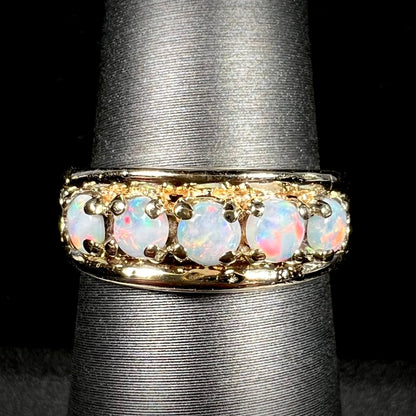 A yellow gold band set with five round cabochon cut opals and heart design accents.